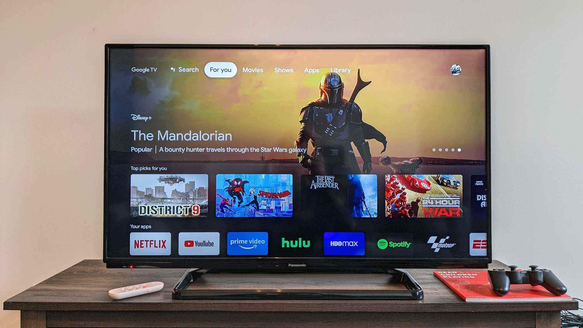 Ahşap bir yüzey üzerinde bir TV'ye yüklenen Google TV ana ekranlı Chromecast