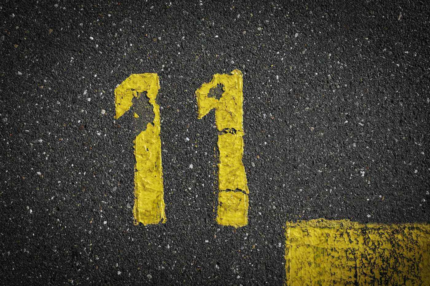 asfaltta işaret, gri sokakta sarı boyalı on bir numara, yoldaki bir köşe gibi sarı çizgiler, metin için alan