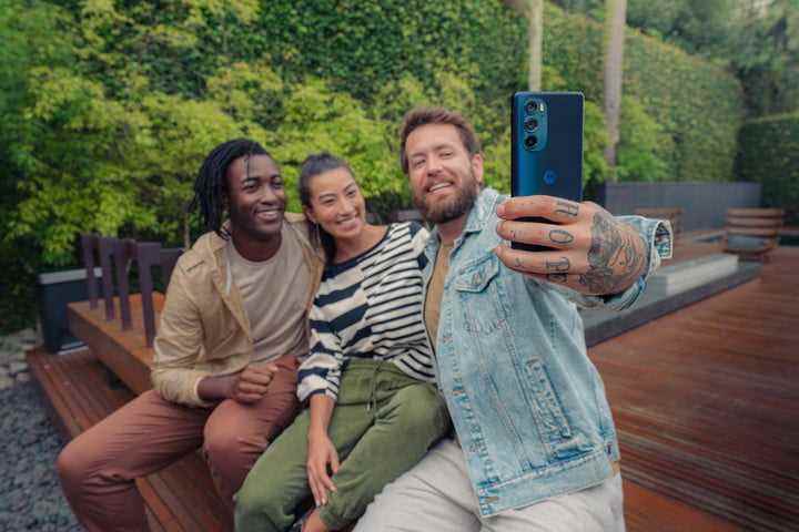 Bir adam Motorola Edge Plus 2022 akıllı telefonu kullanarak arkadaşlarıyla selfie çekiyor.