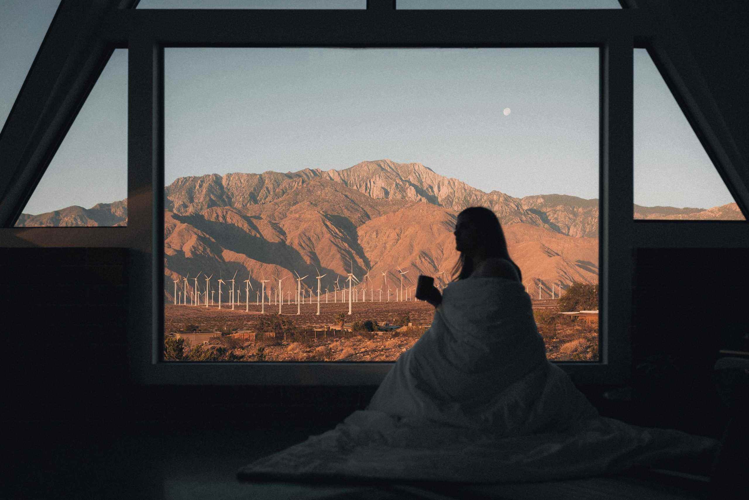 Bir kadın pencereden çöl manzarasına bakıyor.