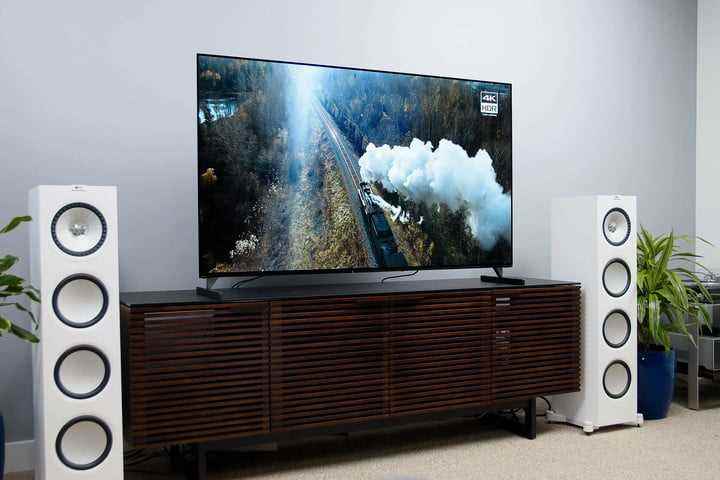 İki beyaz surround ses kulesi hoparlörüyle çevrili bir medya konsolunda bir Sony Bravia XR A90J 4K OLED TV. 