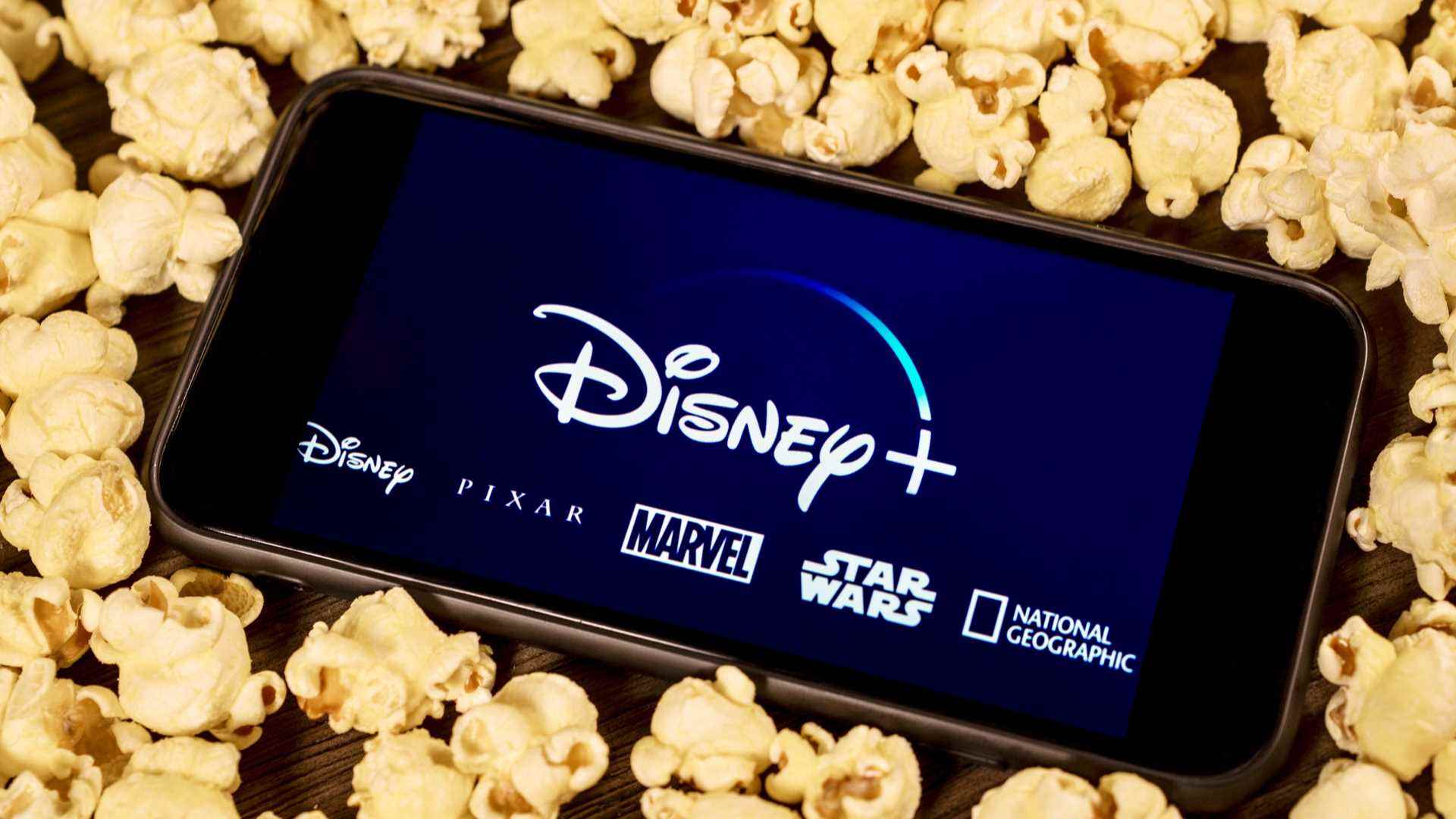 Patlamış mısırla çevrili Disney Plus yüklü bir cep telefonunun görüntüsü