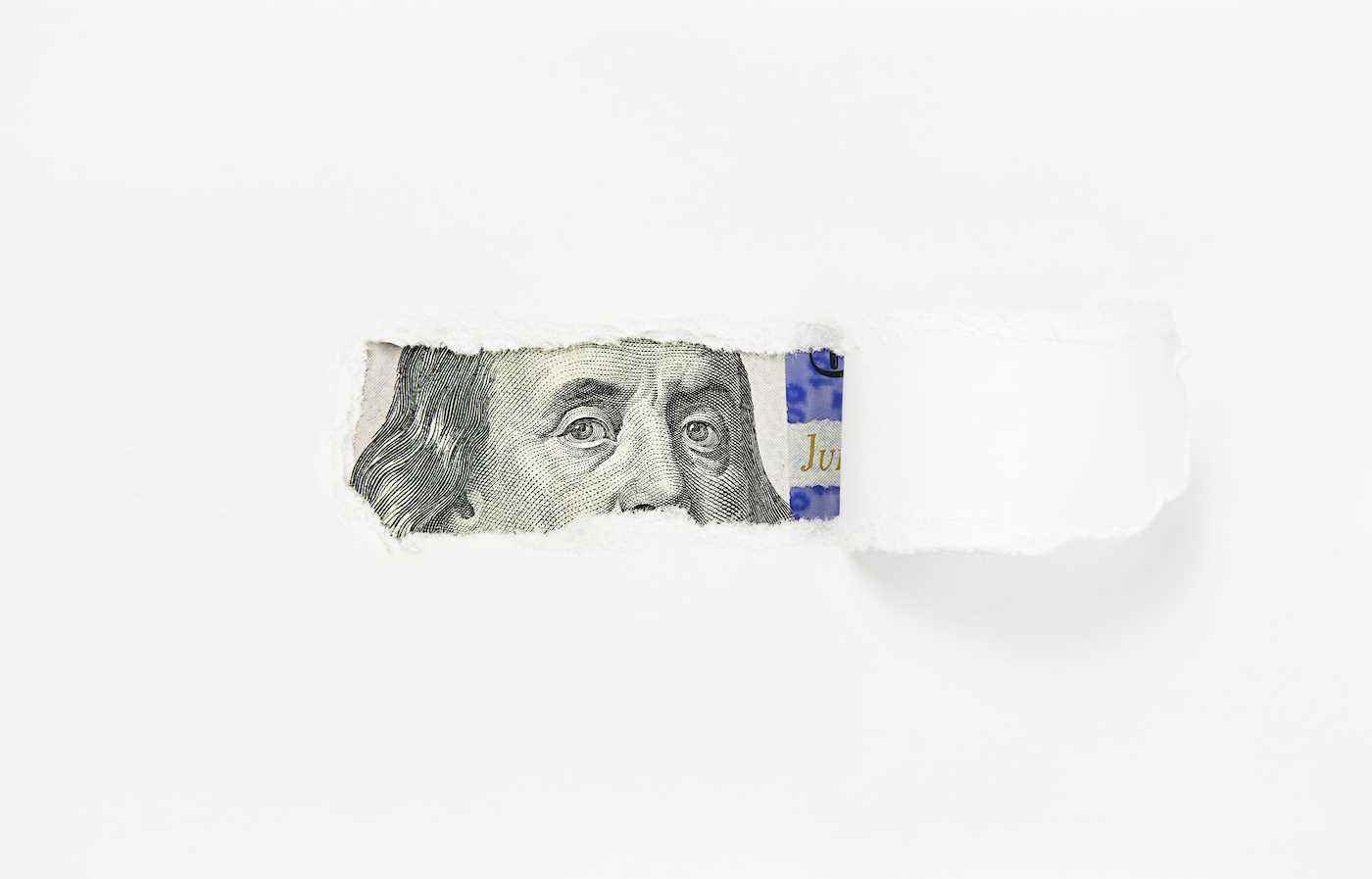 Yırtık kağıt deliğinde yüz dolarlık banknotta Benjamin Franklin portresi, yakın plan