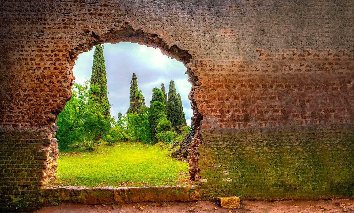 Latina, İtalya'da bir tuğla duvardaki pürüzlü bir delikten görünen yemyeşil bir bahçenin fotoğrafı