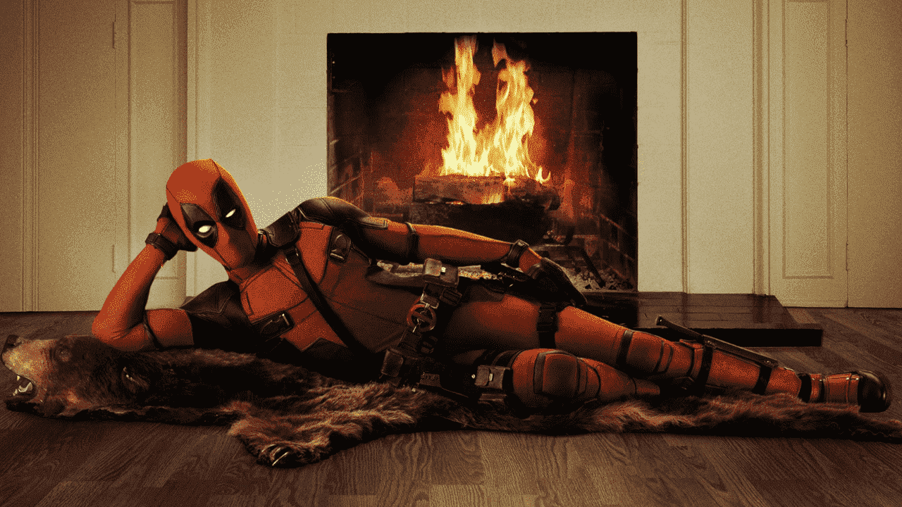 Deadpool yanan bir şöminenin önünde poz veriyor.