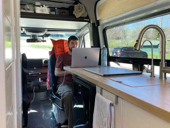 Bir dizüstü bilgisayarda çalışan bir minibüste bir sandalyede oturan bir adam