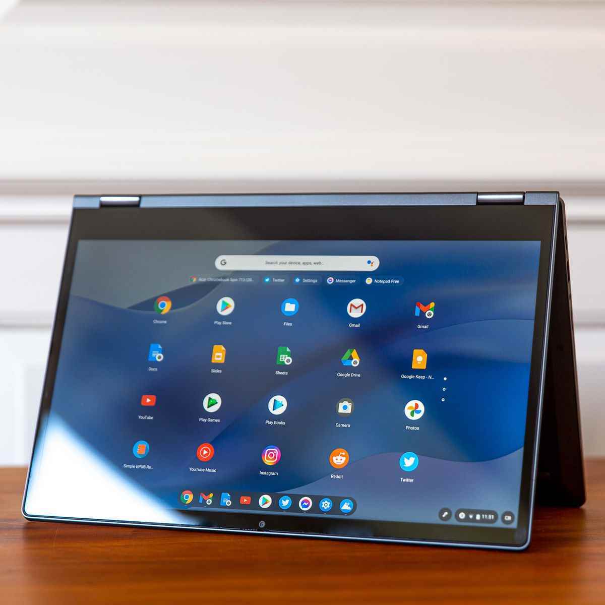 Çadır modunda Lenovo Flex 5 Chromebook, sola açılı.  Ekran, mavi dalgalı bir arka plan üzerinde bir Chrome OS simgeleri ızgarası görüntüler.
