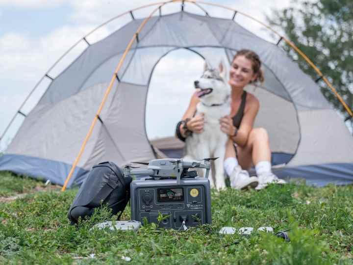 Bir kadın köpeğiyle kamp yaparken kullandığı Bluetti EB3A'yı kullanıyor. 