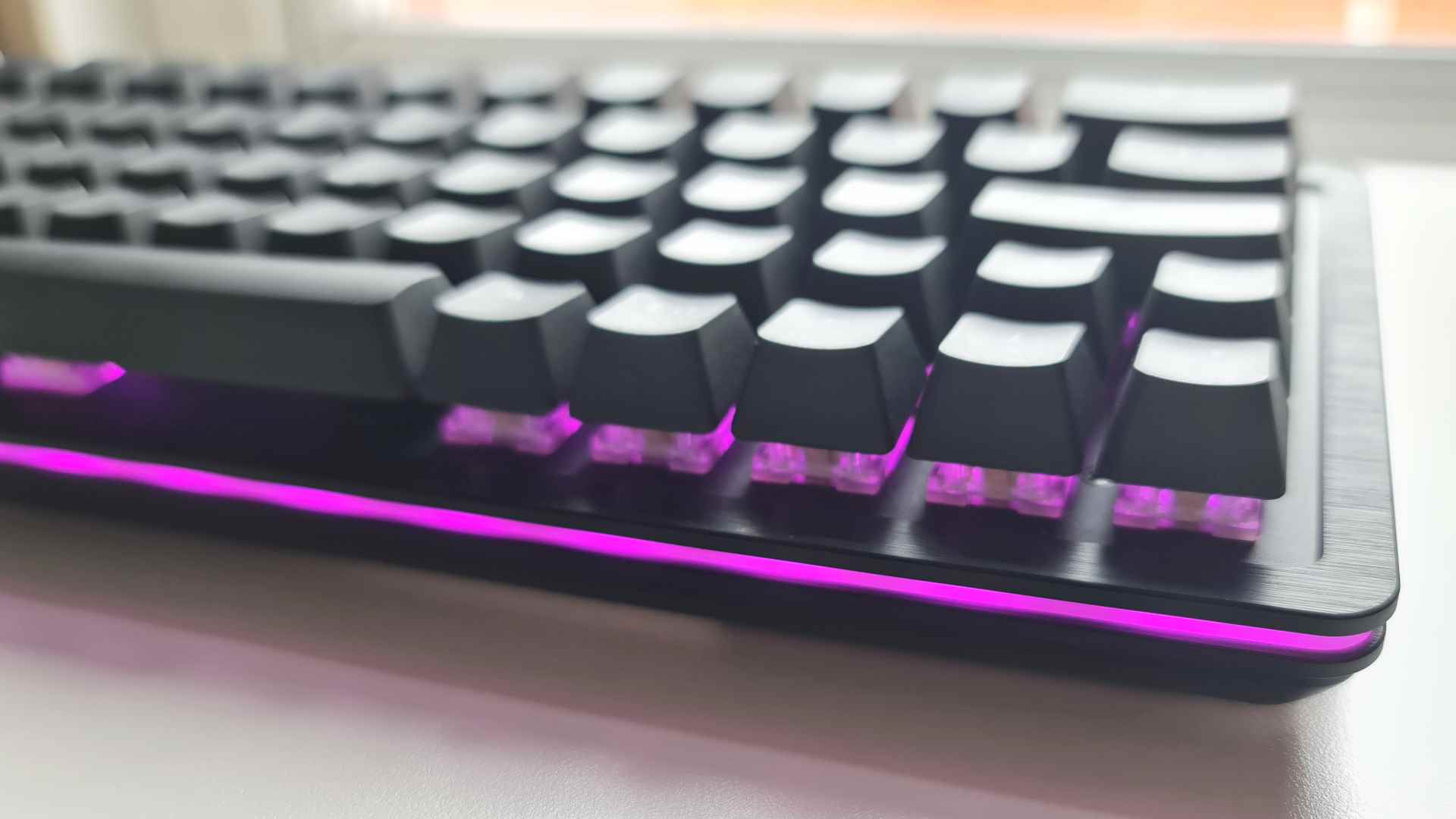 Mountain Everest 60 incelemesi - oyun klavyesinin kenarlarında mor renkte yanan bir RGB aydınlatma şeridi vardır