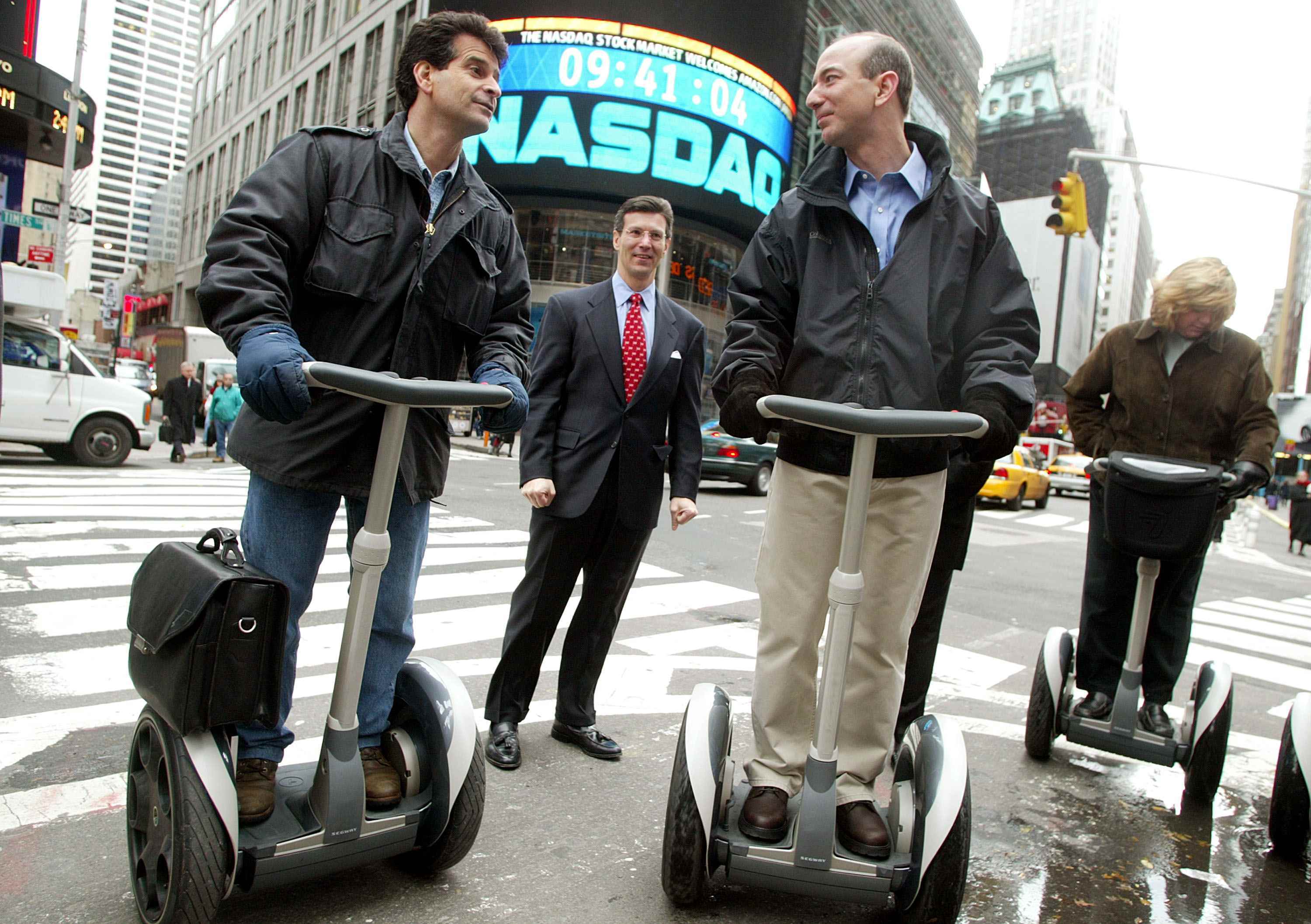 Amazon.com CEO'su Jeff Bezos (R), 18 Kasım 2002'de New York'ta NASDAQ Borsasını açtıktan sonra Segway mucidi Dean Kamen (solda) ve NASDAQ Başkan Yardımcısı David Weild (C) ile birlikte bir Segway üzerinde duruyor