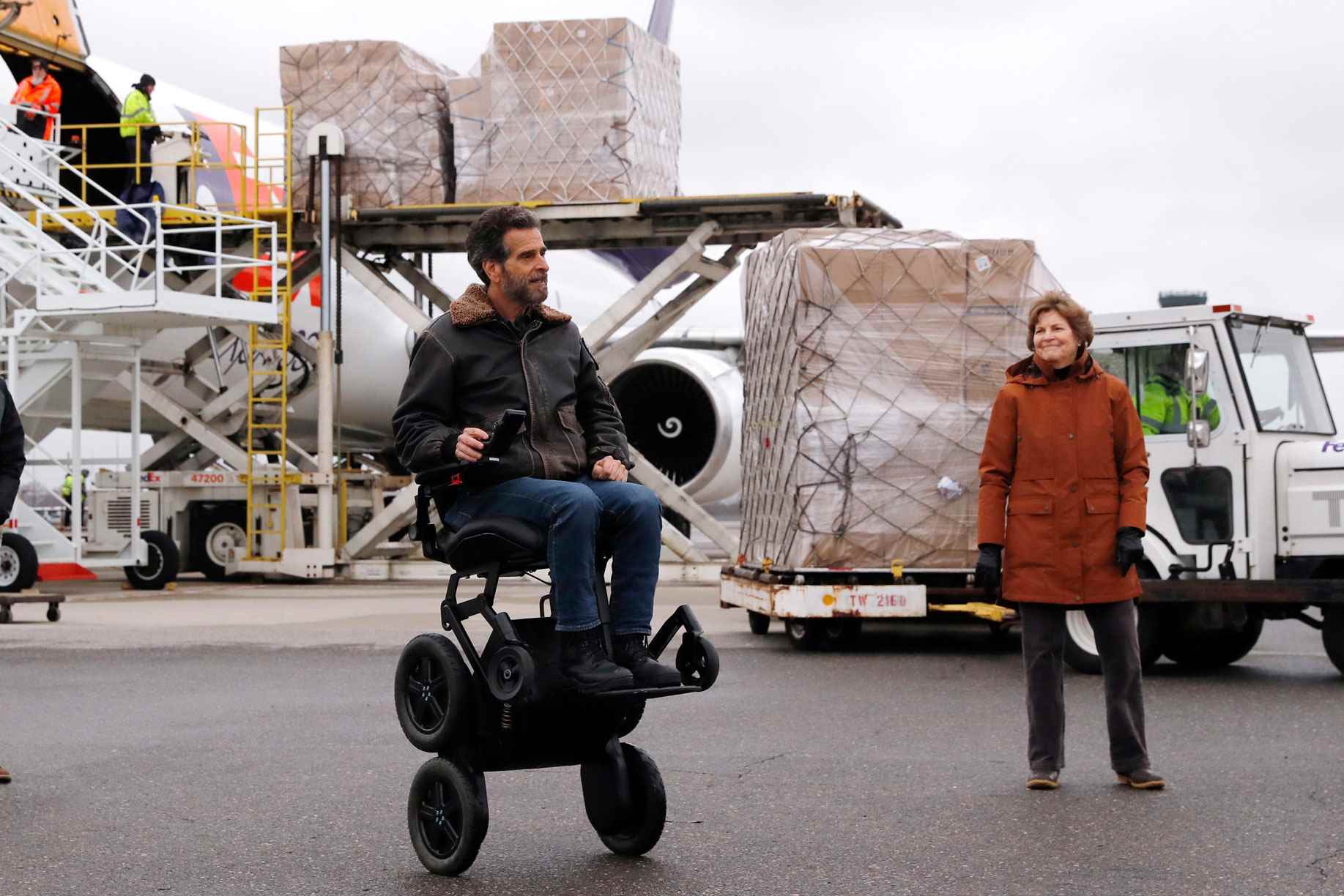 ABD'li Senatör Jeanne Shaheen (D-NH), sağda, tıbbi çalışanları ve COVID-19 virüs salgınıyla mücadele eden ilk müdahale görevlilerini korumak için Çin'in Şanghay kentinden 110.000 pound'dan fazla kişisel koruyucu ekipman (KKD) teslim edildiğinden mucit Dean Kamen'e bakıyor. 30 Nisan 2020 Perşembe, Manchester, New Hampshire'daki Manchester-Boston Bölge Havaalanında bir kargo uçağından boşaltıldı