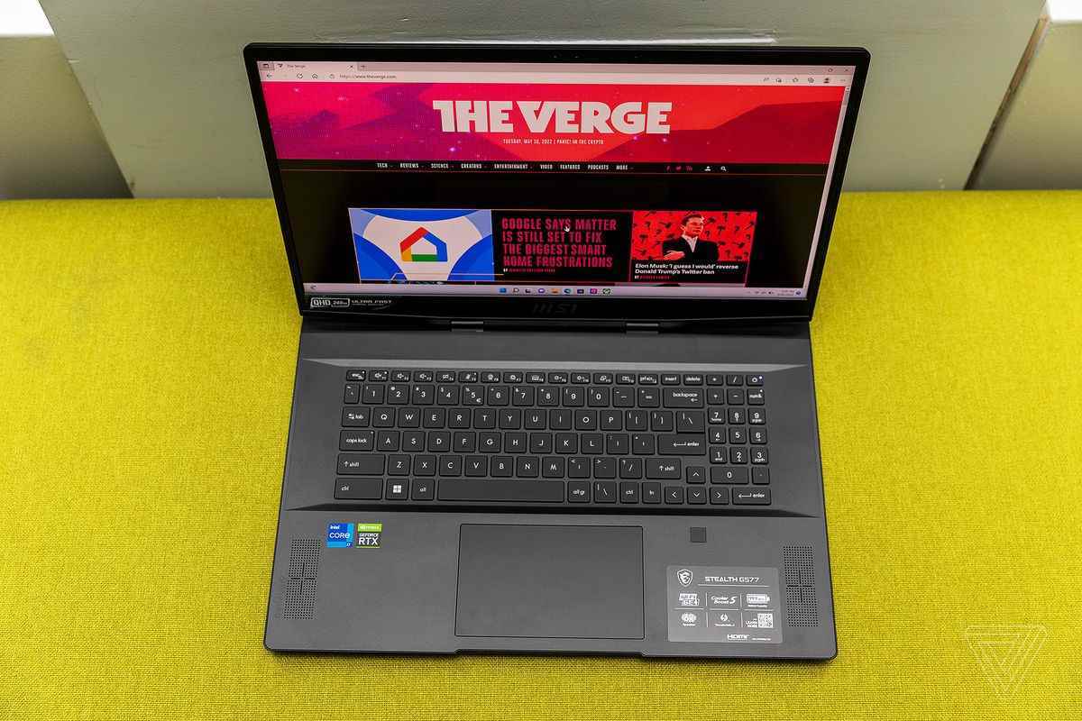 Sarı kumaş bir bankta yukarıdan görülen MSI GS77 Stealth klavye destesi.  Ekranda The Verge ana sayfası görüntülenir.