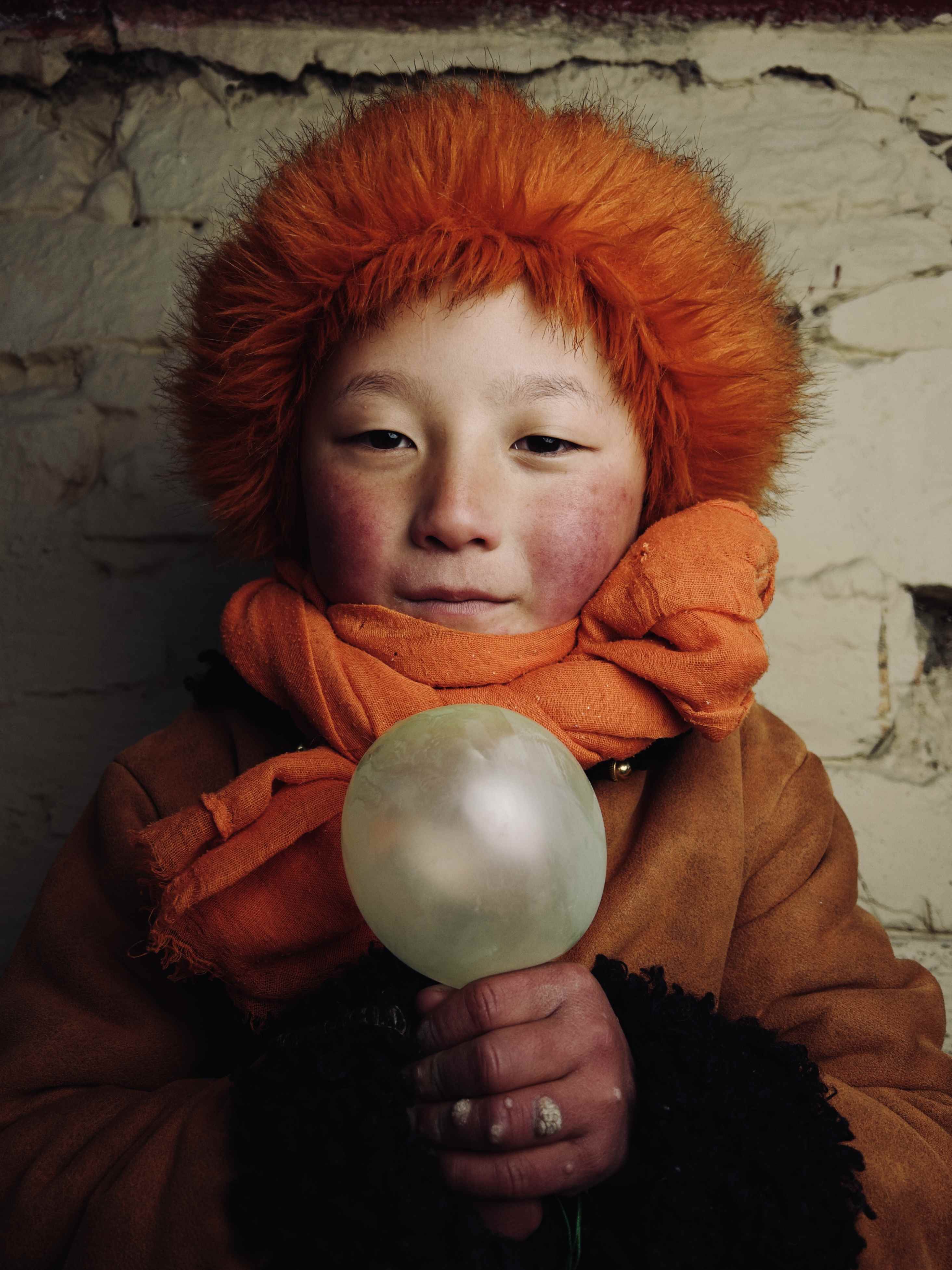 Bir balon tutan turuncu saçlı bir çocuk