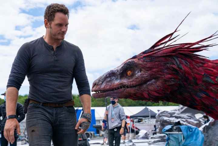 Chris Pratt, Jurassic World Dominion setinde bir Pyroraptor kafa modelinin yanında duruyor.