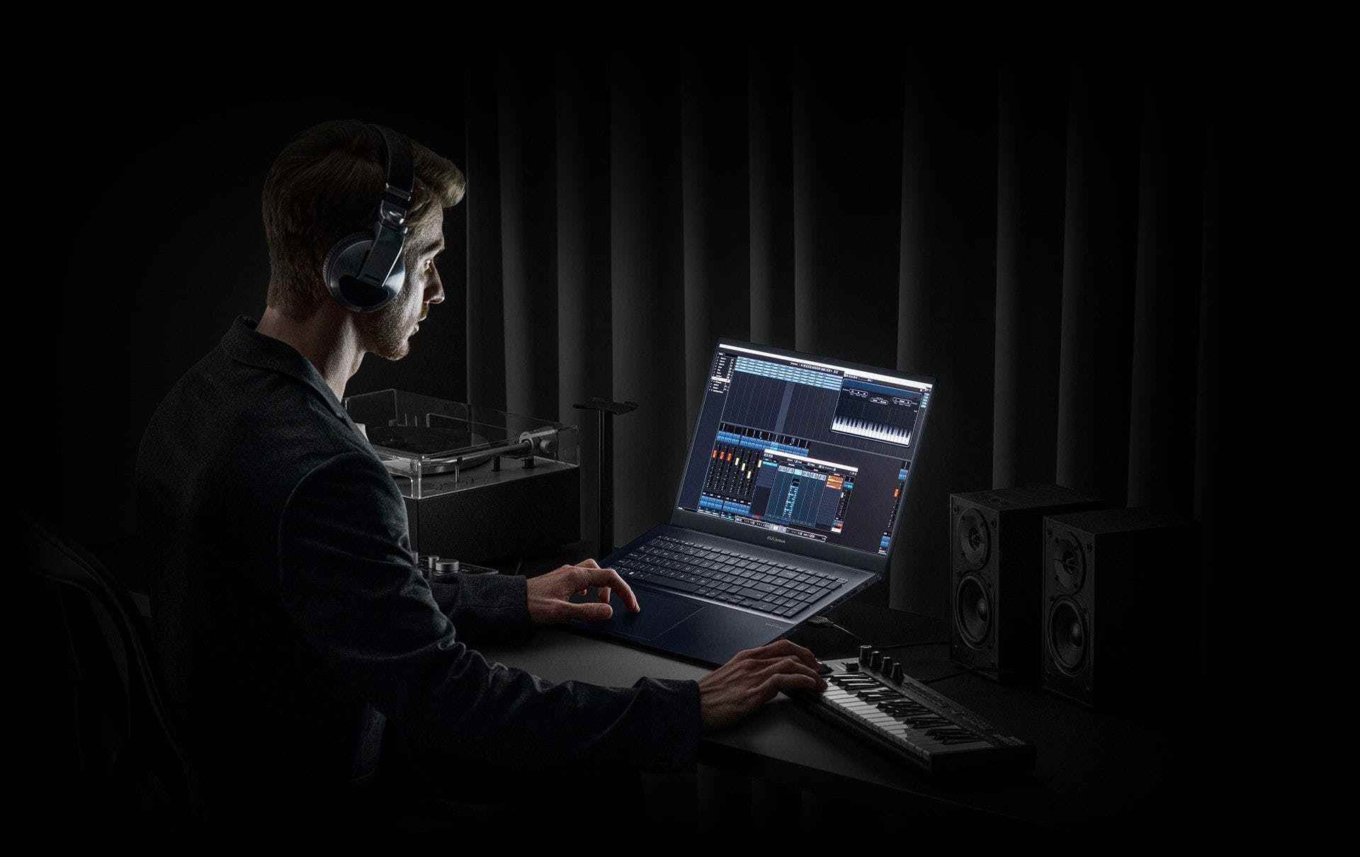 Bir kullanıcı, bir dizi hoparlörün yanındaki karanlık bir stüdyoda Zenbook Pro 17'de sesi düzenler.