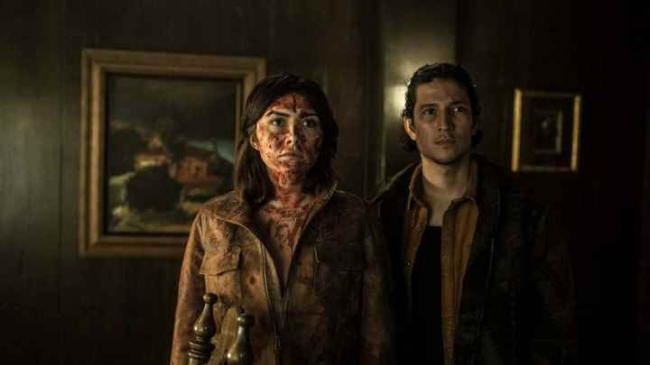 Tales of the Walking Dead'den bir sahnede kanlar içinde genç bir çift bir evde duruyor.