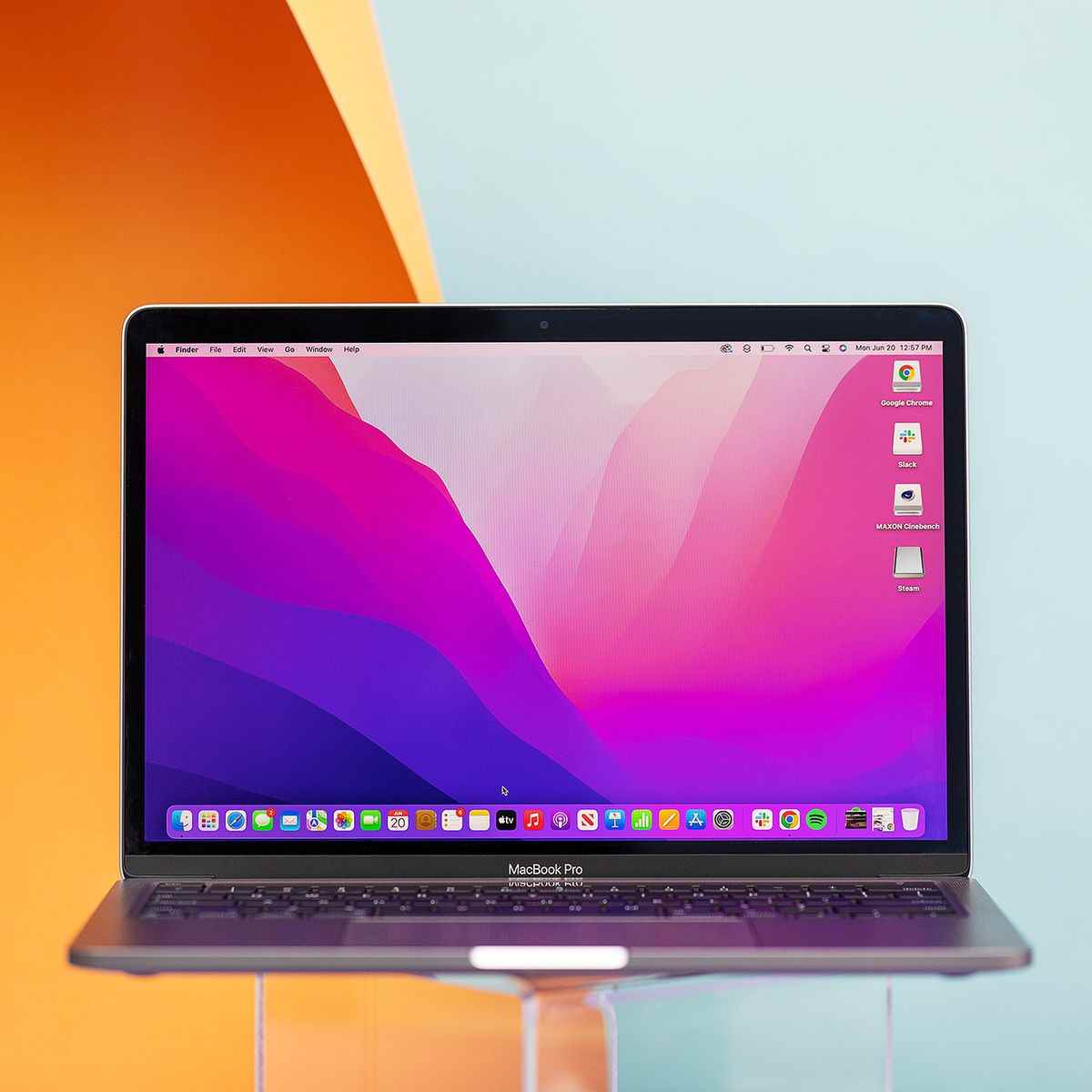 MacBook Pro 13 2022 şeffaf bir stand üzerinde açılır.  Ekranda pembe ve mor bir masaüstü arka planı görüntülenir.