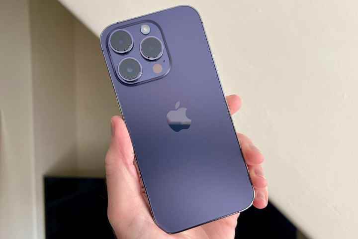 Bir erkeğin elinde tutulan Deep Purple renkli iPhone 14 Pro.