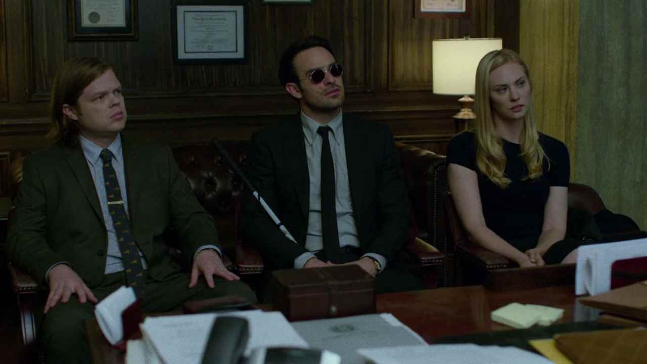 Matt, Foggy ve Karen, Netflix'teki Daredevil'de kamera dışından birini dinleyip izlerken ofislerinde oturuyorlar