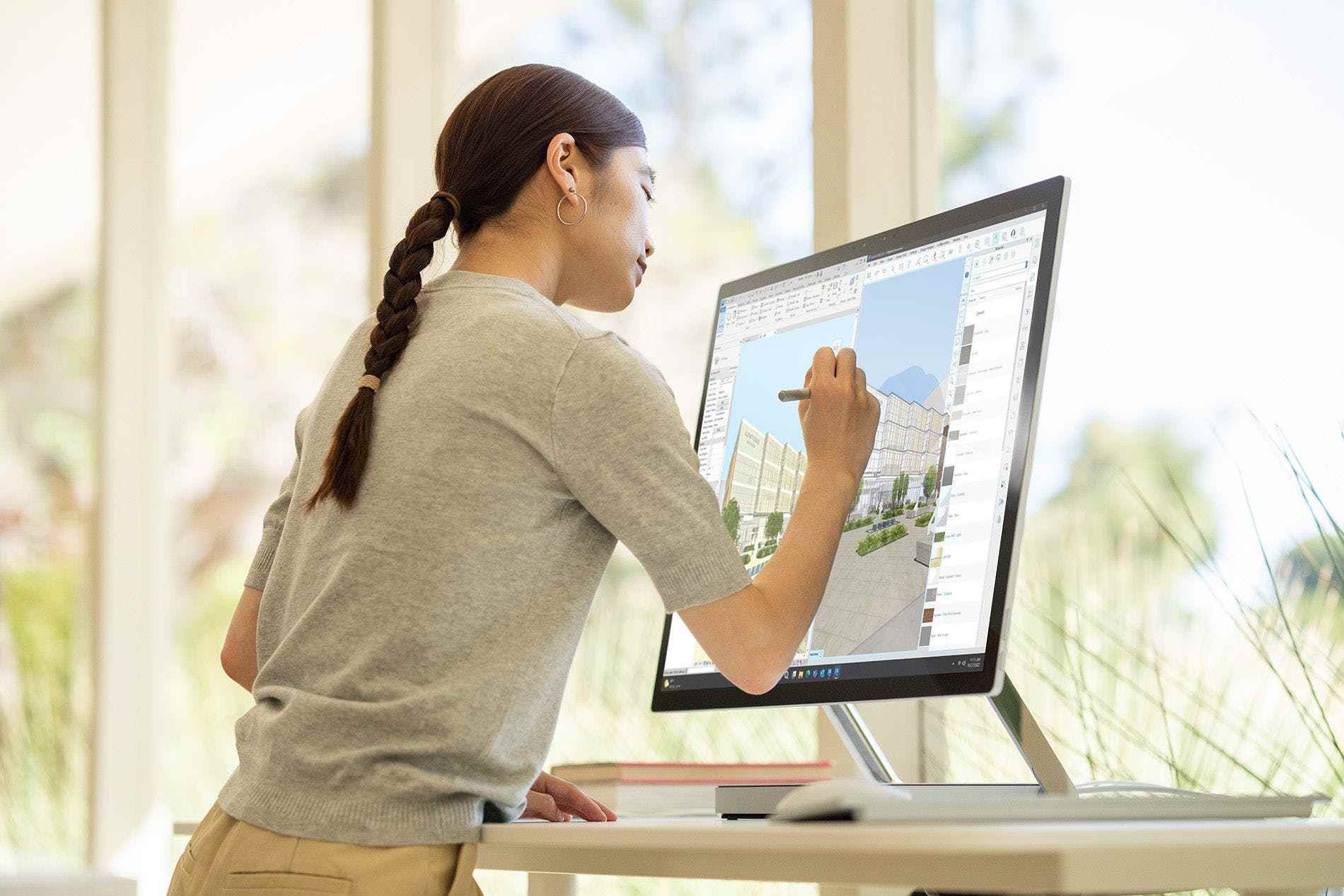 Bir kullanıcı, ayakta duran bir masada Surface Studio 2 Plus'ta ekran kalemi ile çizim yapıyor.