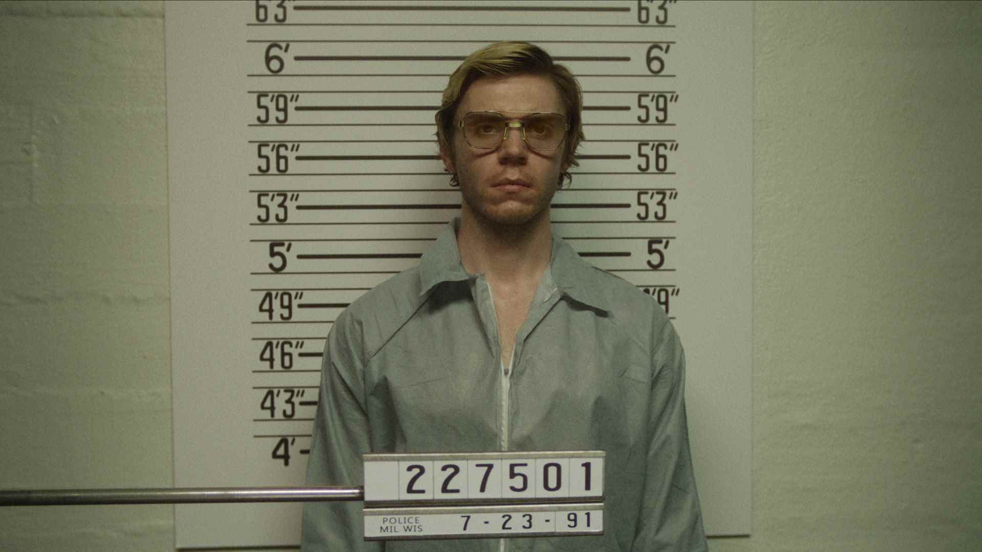 Evan Peters'in Jeffrey Dahmer'ı Monster: The Jeffrey Dahmer Story'de polis fotoğrafı çekilirken bir ölçüm duvarının önünde duruyor