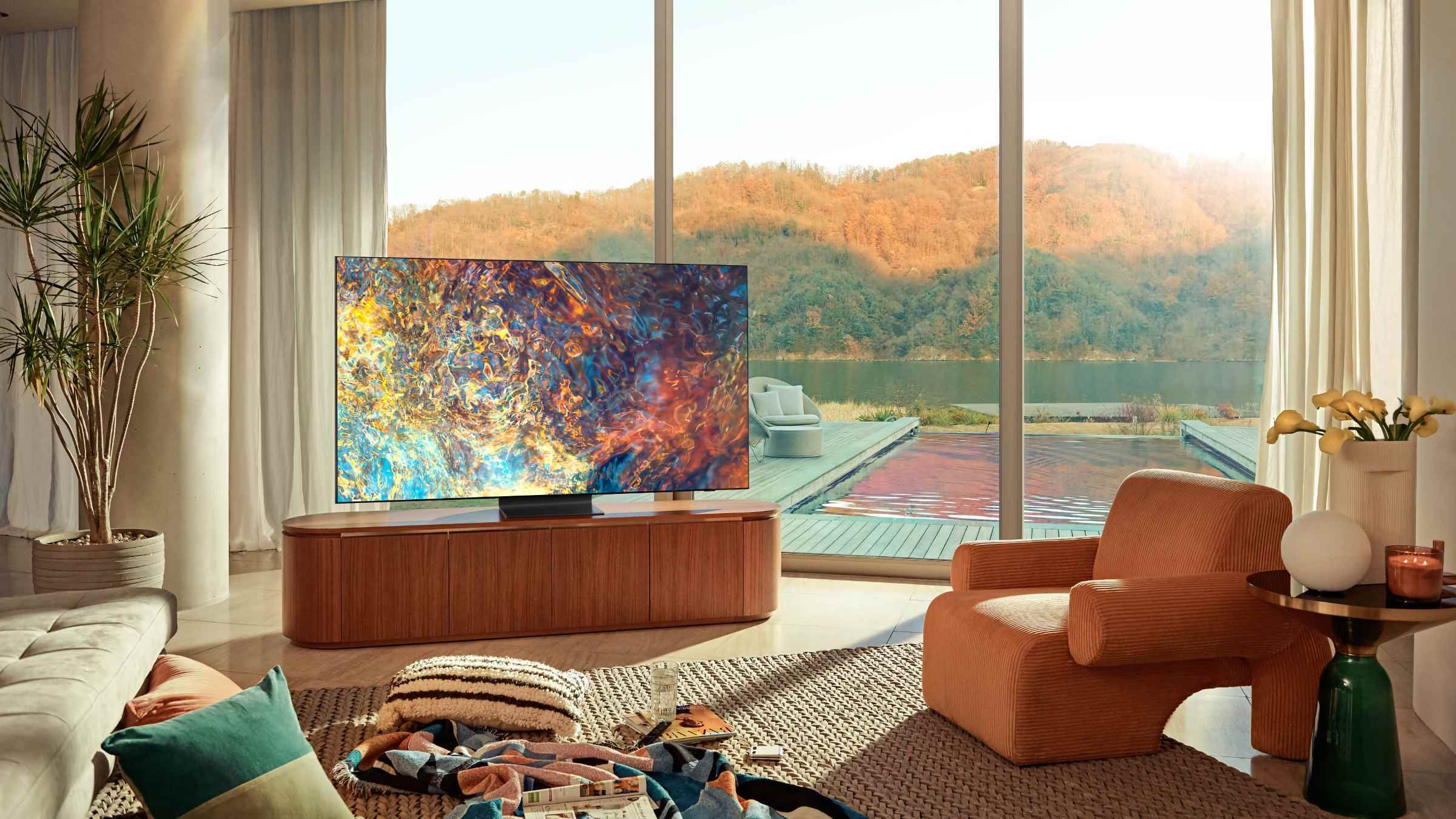 Aydınlık bir oturma odasındaki Samsung'un Mini-LED TV'lerinden biri, ekranında renkli, soyut bir resim gösteriliyor.