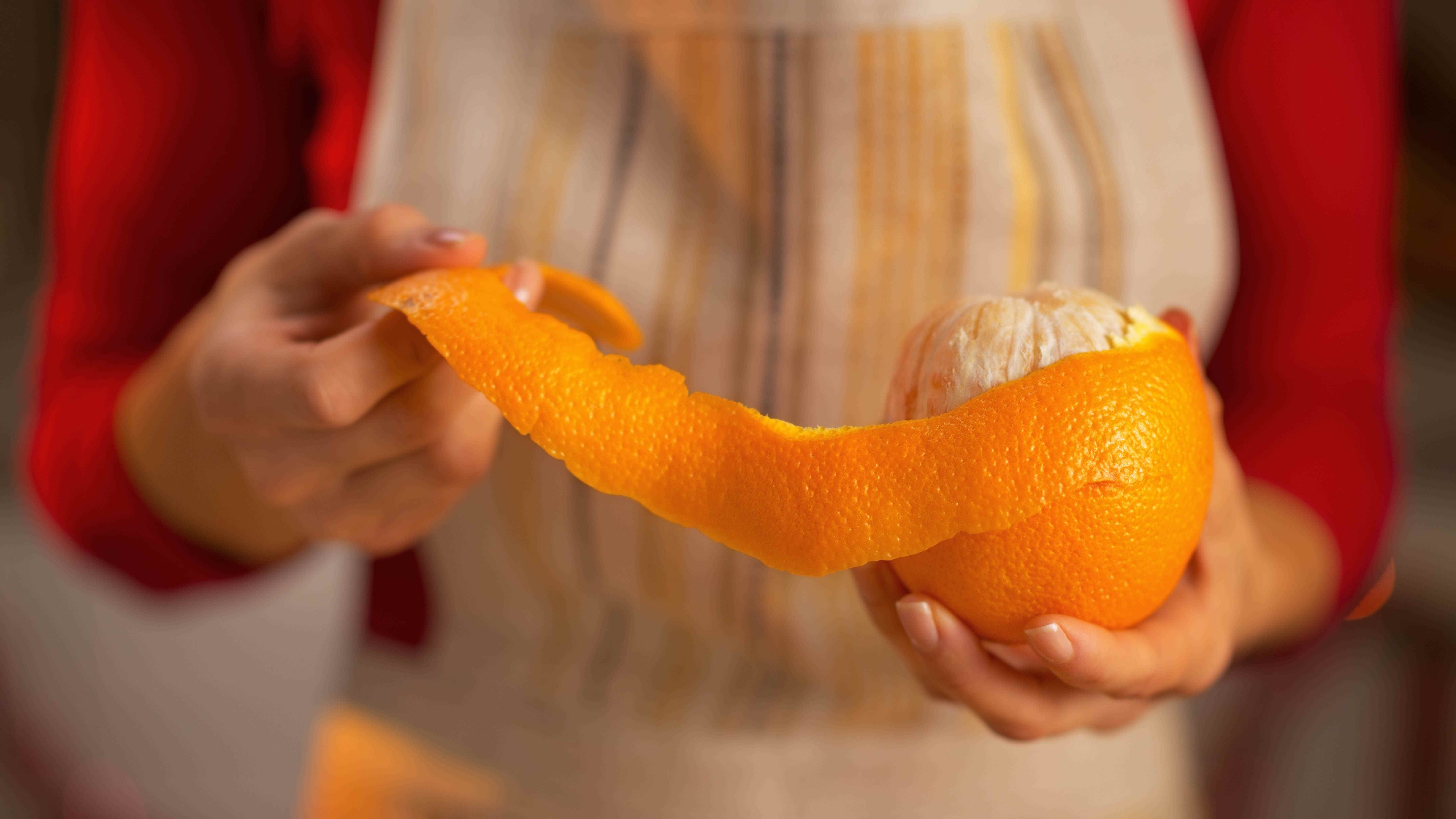 Birisi elinde bir portakal tutuyor ve kabuğunu soyuyor