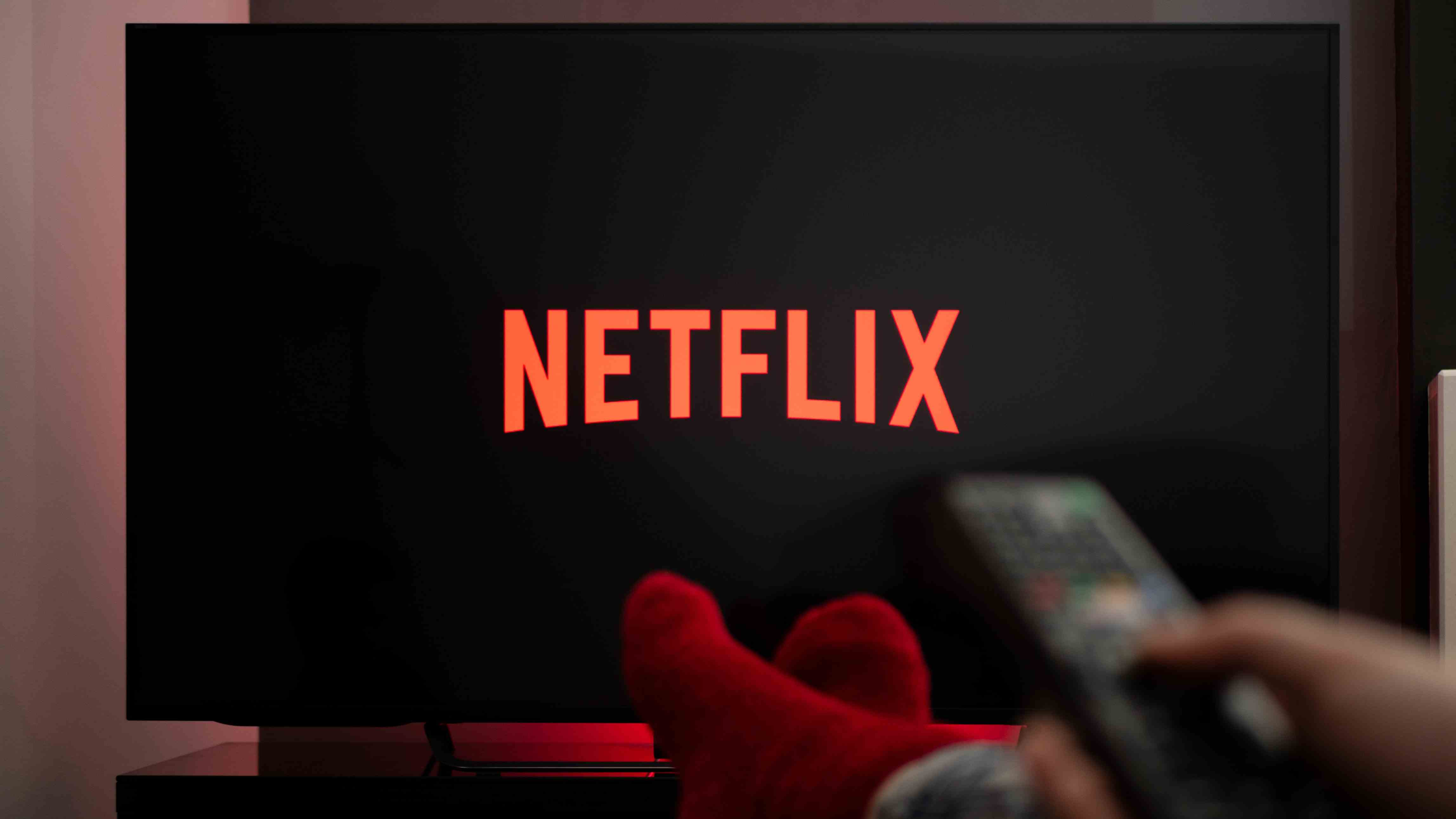 TV'de Netflix izlerken ayakları masanın üzerinde olan adam