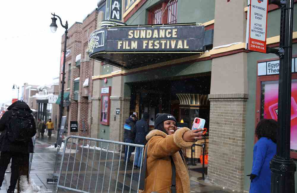 Bir festival müdavimi, 21 Ocak 2023'te Utah, Park City'de düzenlenen 2023 Sundance Film Festivali sırasında Mısır Tiyatrosu'nun önünde selfie çekiyor.