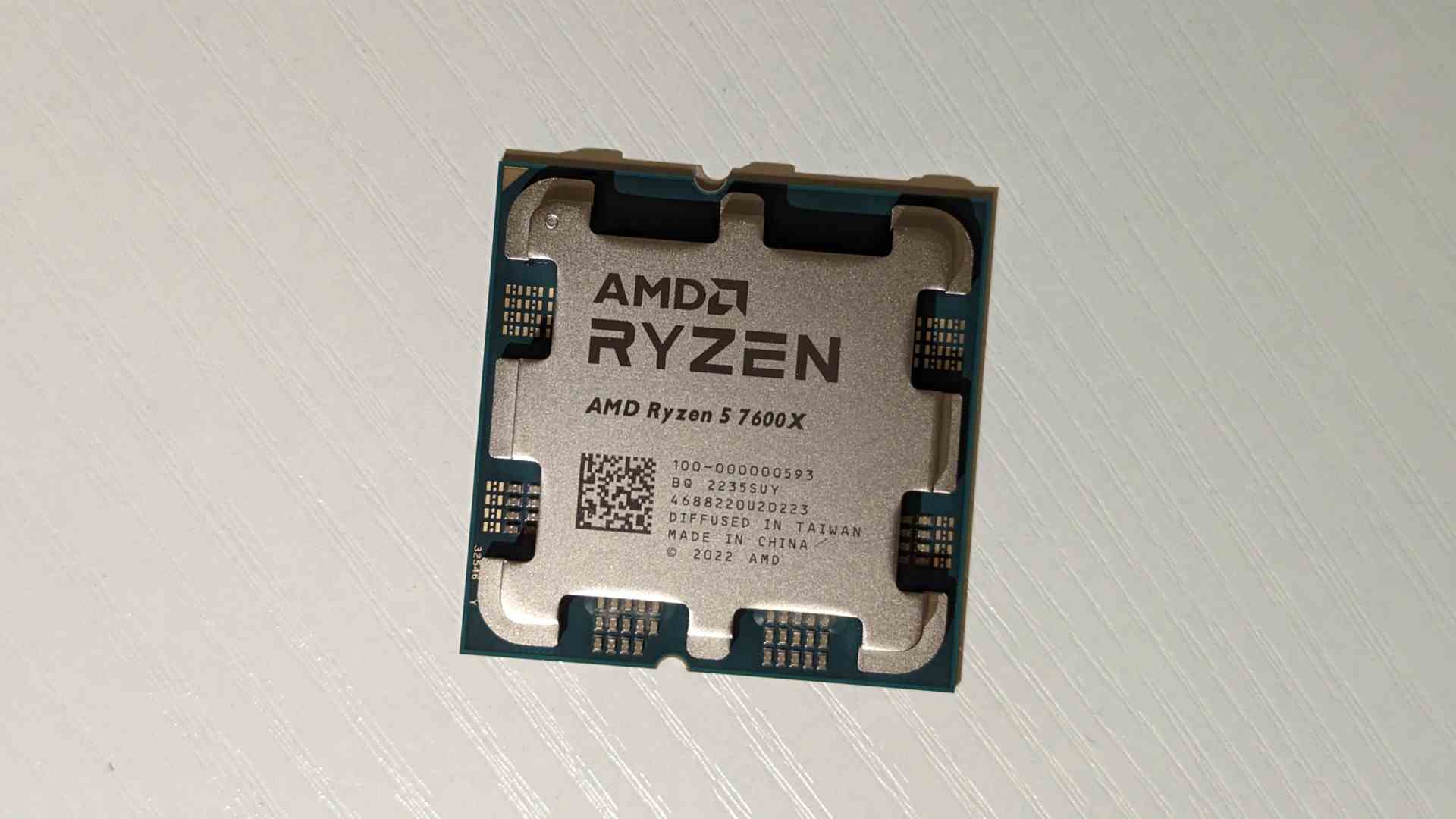 Beyaz ahşap bir masanın üzerinde duran AMD Ryzen 5 7600X işlemci