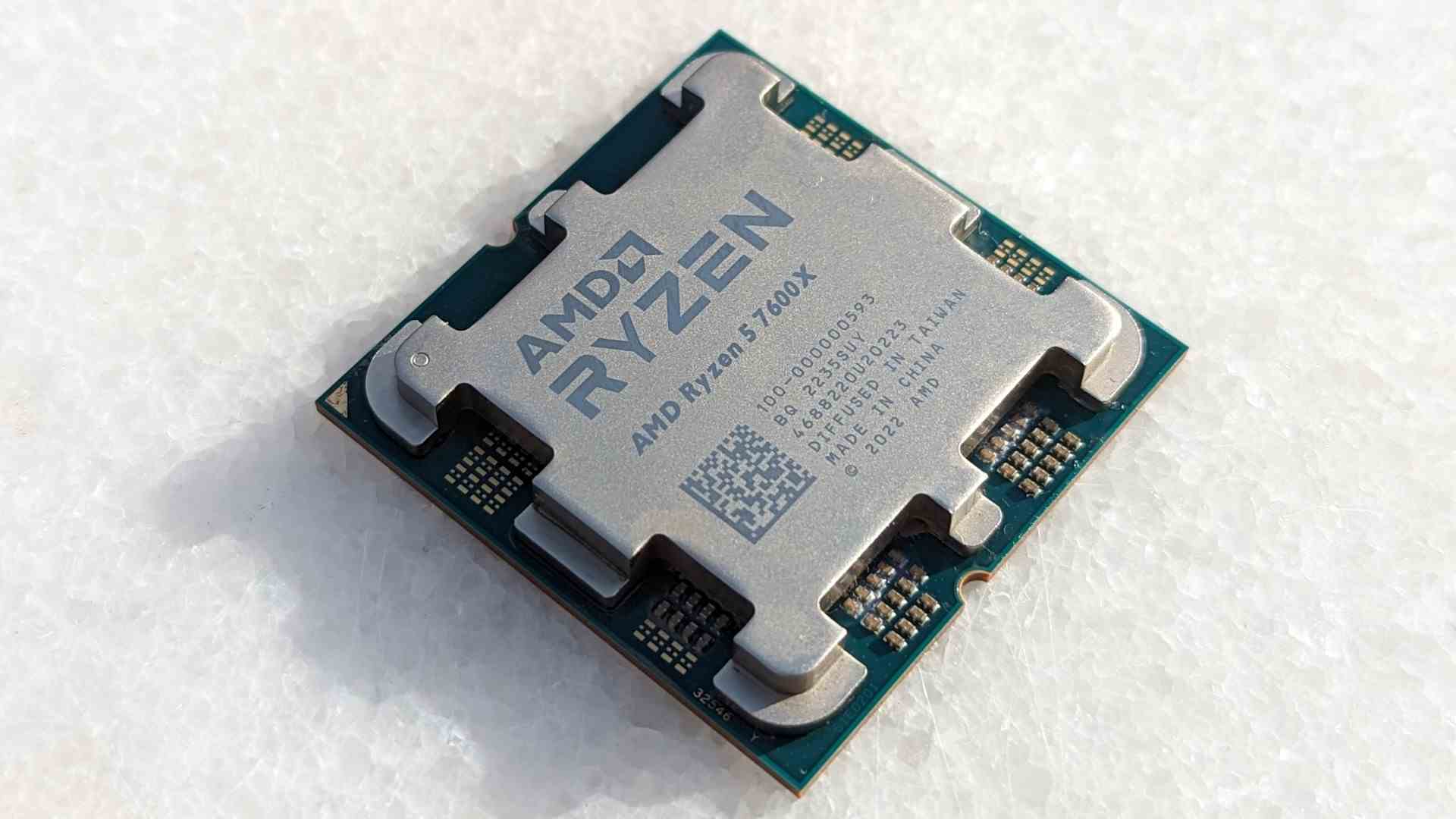 Beyaz taş bir masanın üzerinde yatan AMD Ryzen 5 7600X işlemci
