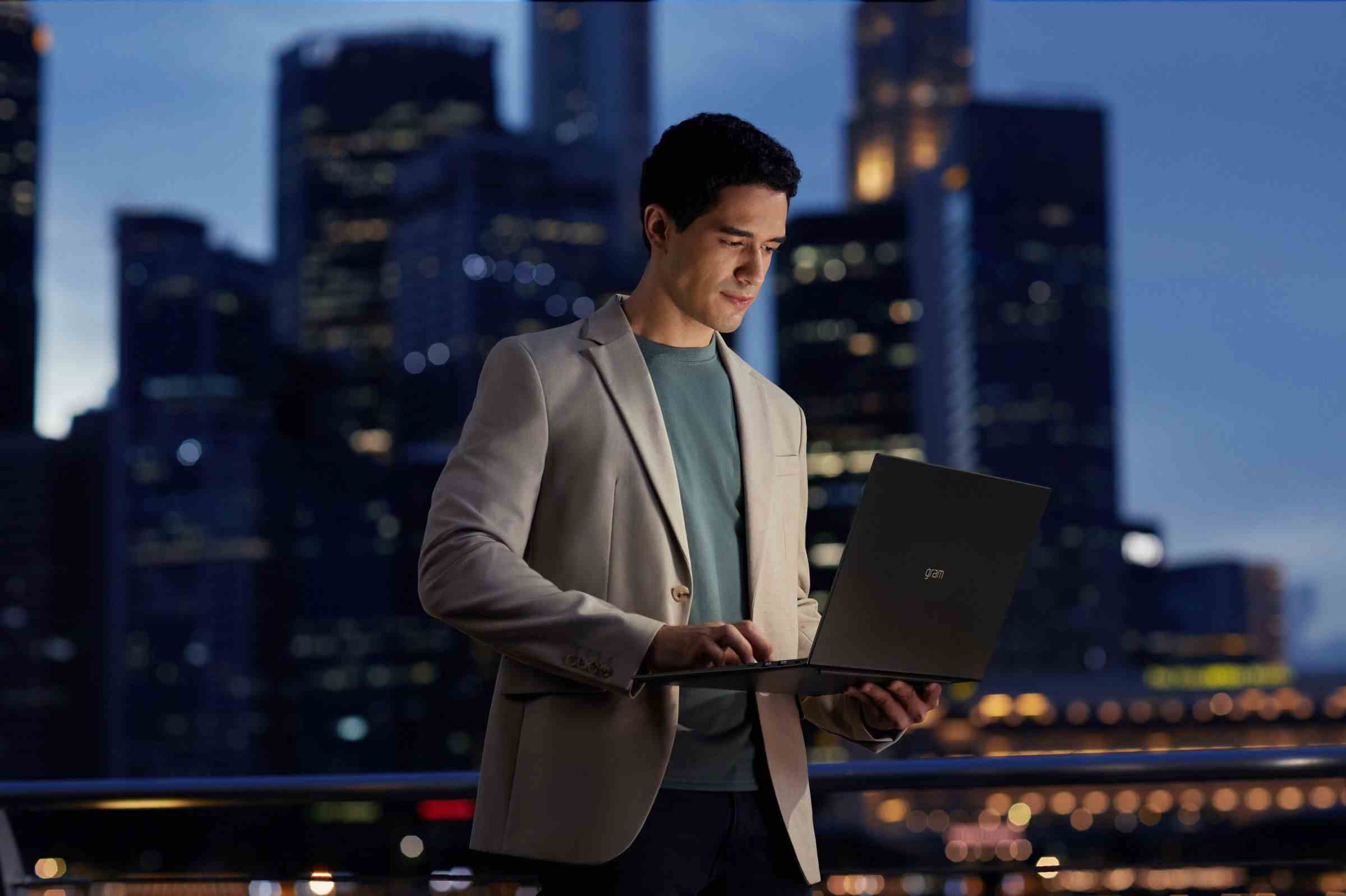 Bir kullanıcı, gece şehir manzarası ortamında bir LG Gram dizüstü bilgisayarda çalışıyor.