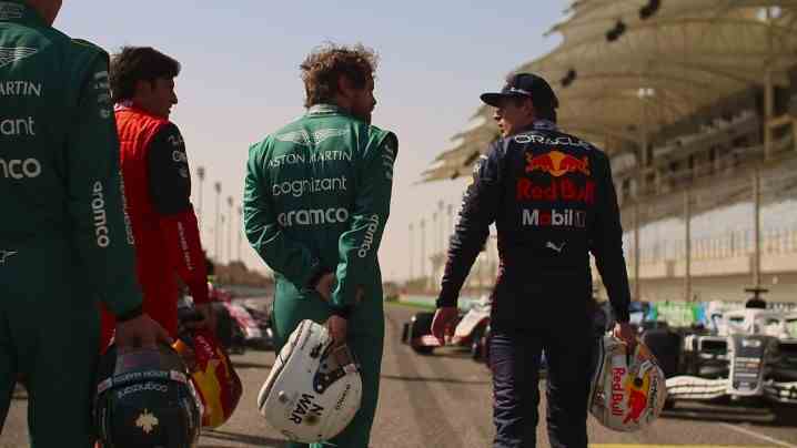 Red Bull takımından Max Verstappen de dahil olmak üzere birçok sürücü, Formula 1: Drive to Survive'ın 5. sezonundan bir sahnede, kasklarını tutarak pist boyunca yürüyor.