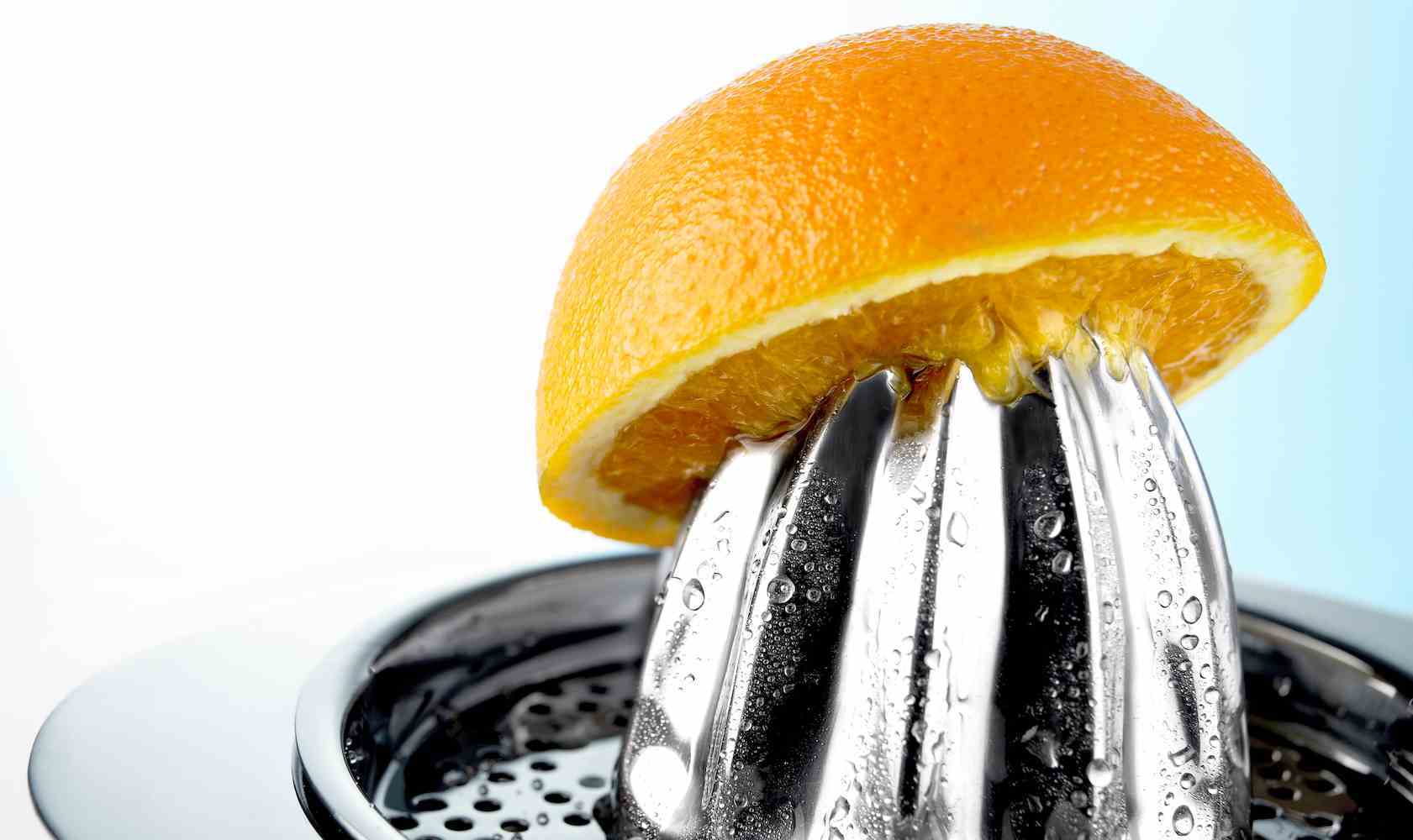 metal bir meyve sıkacağı üzerinde dengelenmiş bir portakalın yarısı