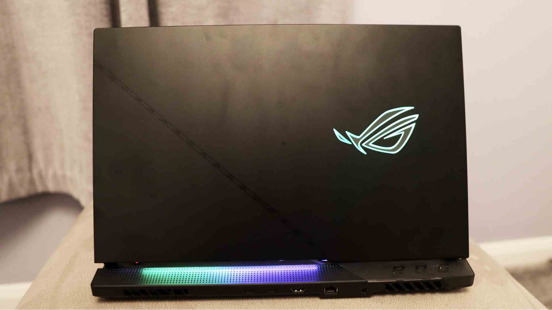Asus ROG Strix Scar 17 incelemesi: Bej bir stand üzerine yerleştirilmiş, plastik kasası bir RGB logosuyla aydınlatılmış bir oyun dizüstü bilgisayarı