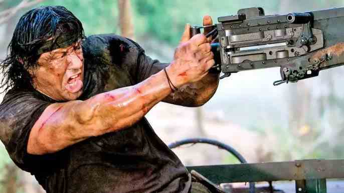 Sylvester Stallone, Rambo rolünde, elinde bir silahla ve kızgın görünüyor