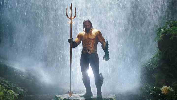 Aquaman filminde trident tutan bir şelalenin önünde duran Aquaman.