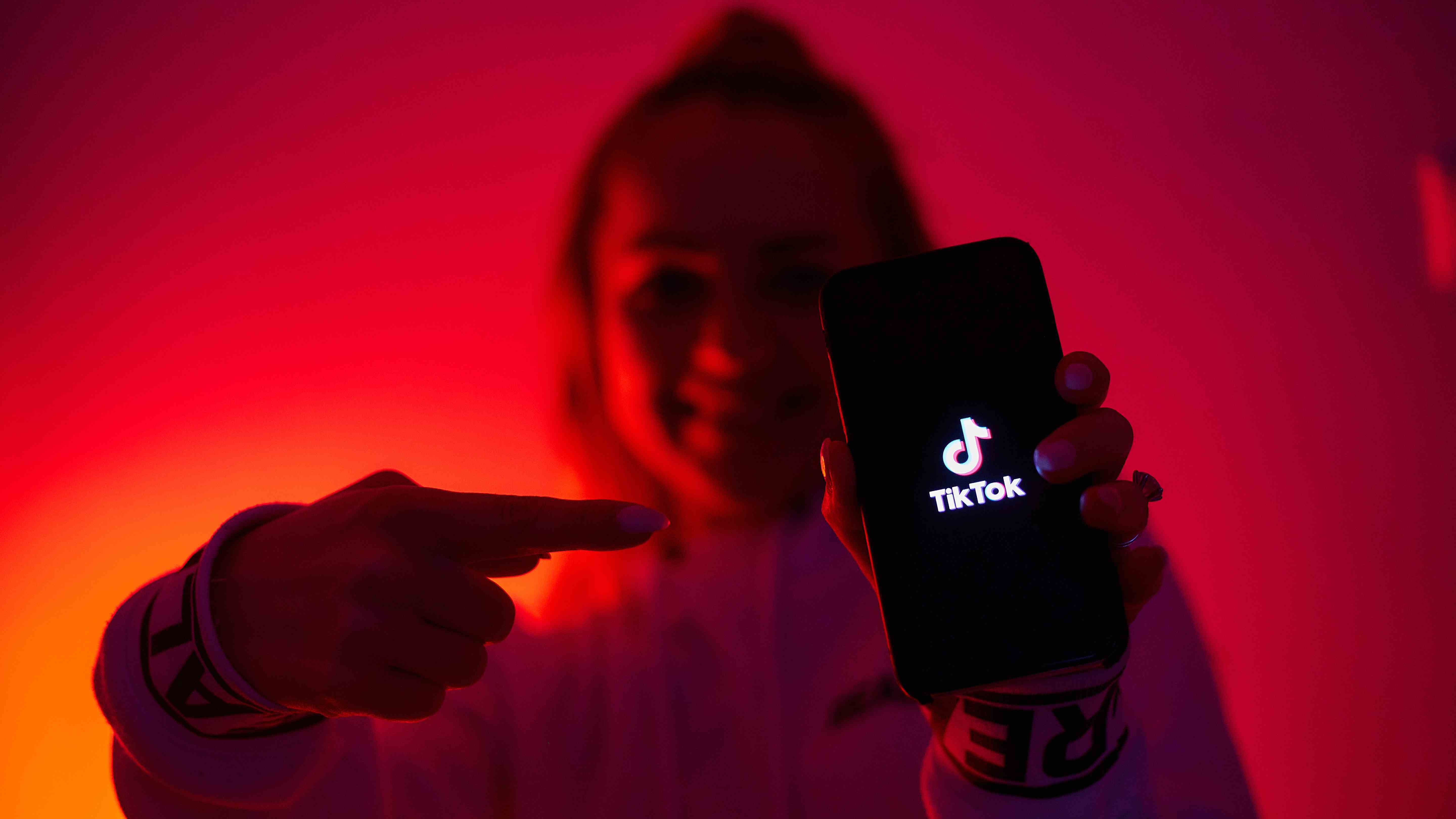 Karanlık tarafı olan bir kız, elinde bir akıllı telefonla sosyal ağı tanıtan tiktok.