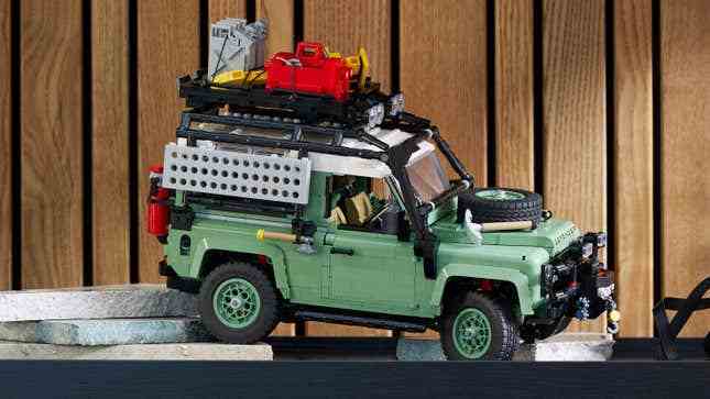 Açık hava macera aksesuarlarıyla donatılmış bir rafta duran Lego Land Rover Defender 90'ın yandan görüntüsü.