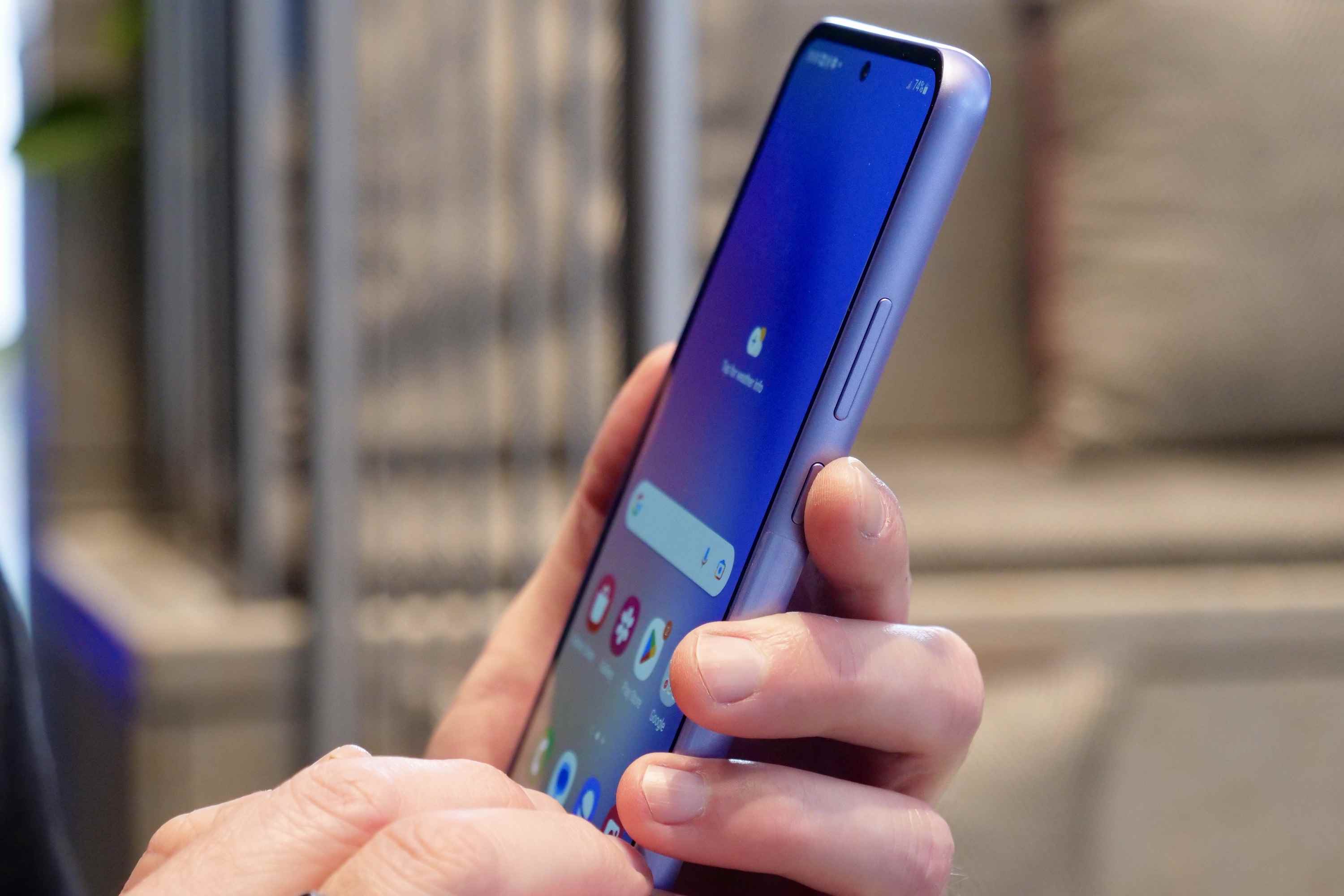 Düğme konumunu gösteren Galaxy A54'ü tutan bir kişi.