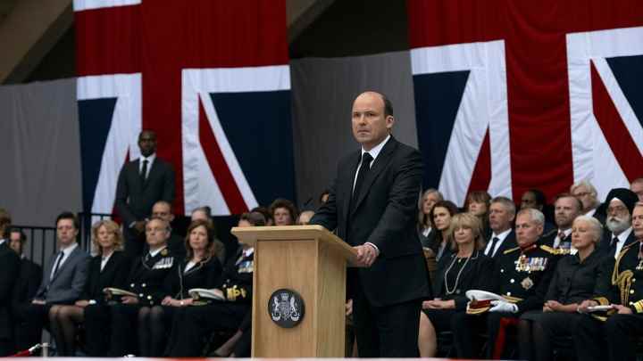 Netflix'te yayınlanan The Diplomat'tan bir sahnede Başbakan Trowbridge kürsüde duruyor.