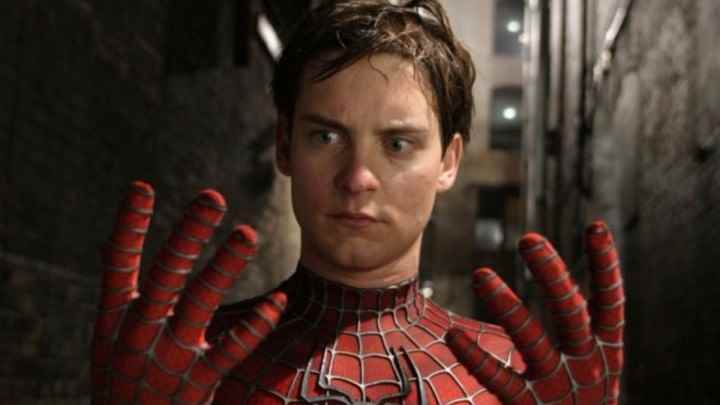 Spider-Man 2'de kafası karışmış halde ellerine bakan maskesiz Spider-Man.