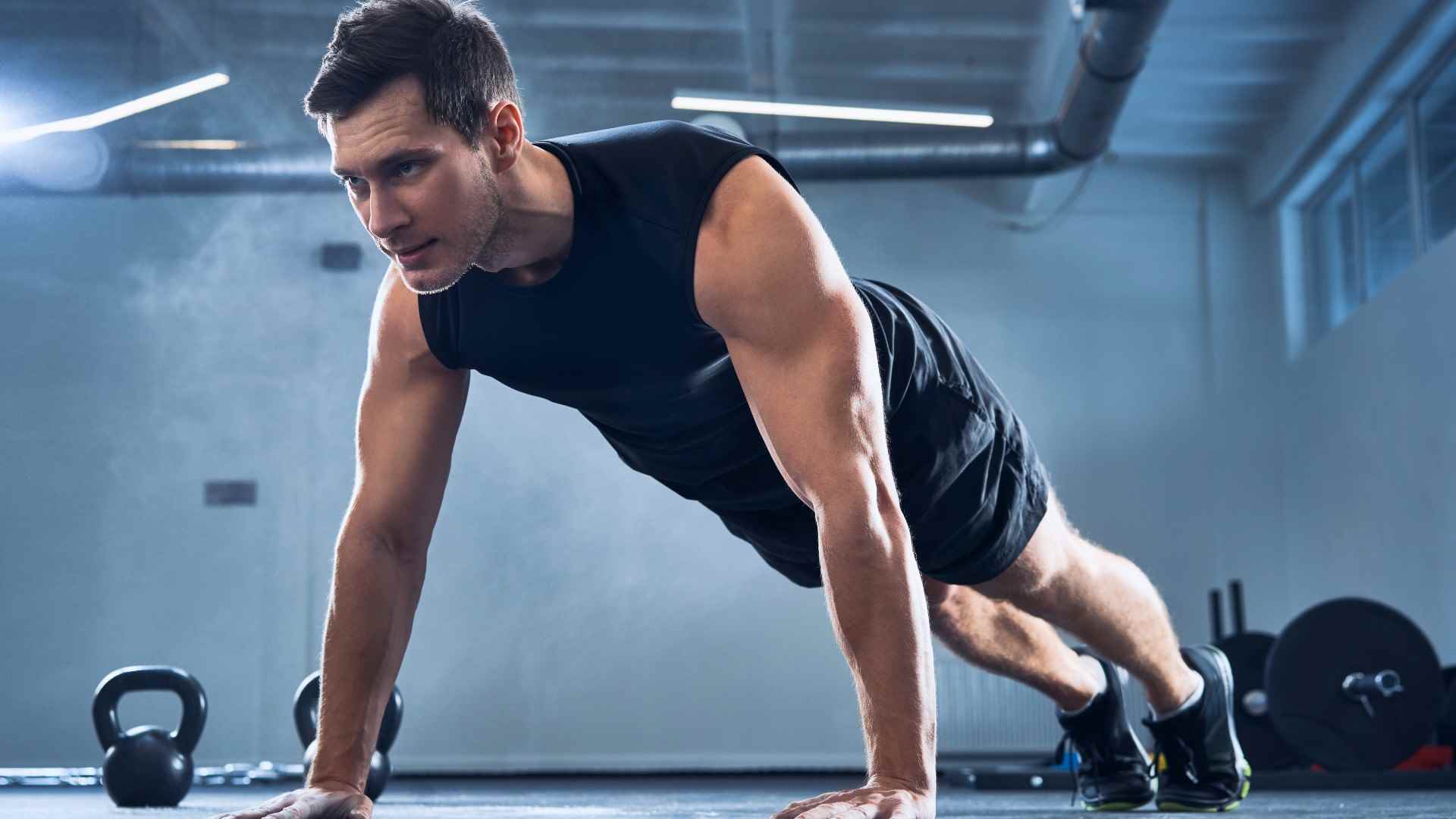 Vücut ağırlığı antrenmanı sırasında spor salonunda geniş bir şınav çeken adam