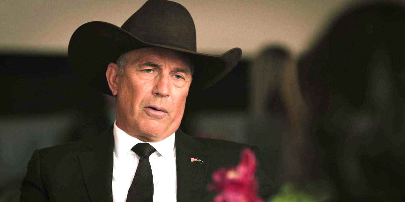 Kevin Costner, Yellowstone'da siyah kovboy şapkasıyla resmi bir davette masada sohbet ederken
