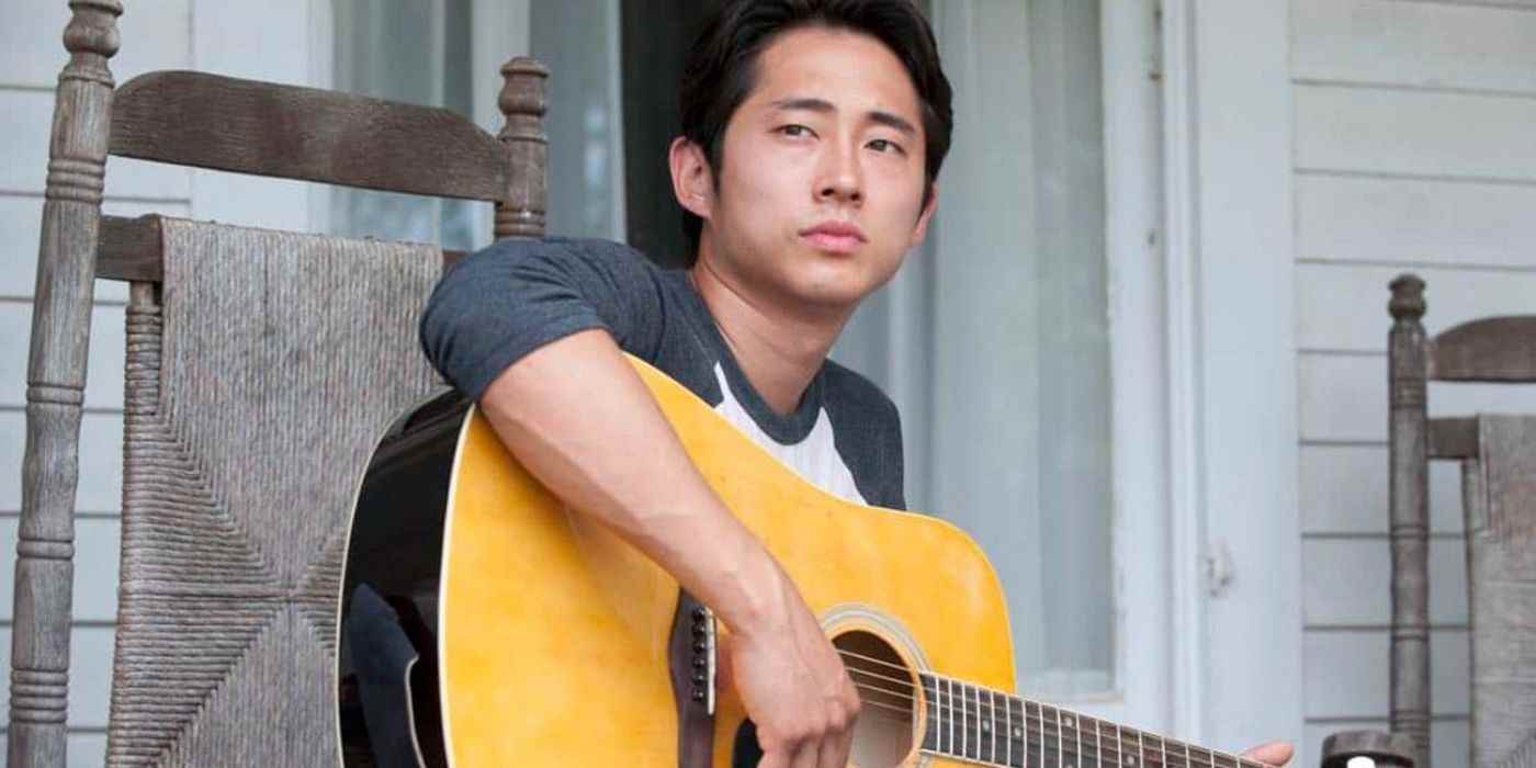 The Walking Dead'de elinde gitar tutan bir sandalyede oturan Glenn