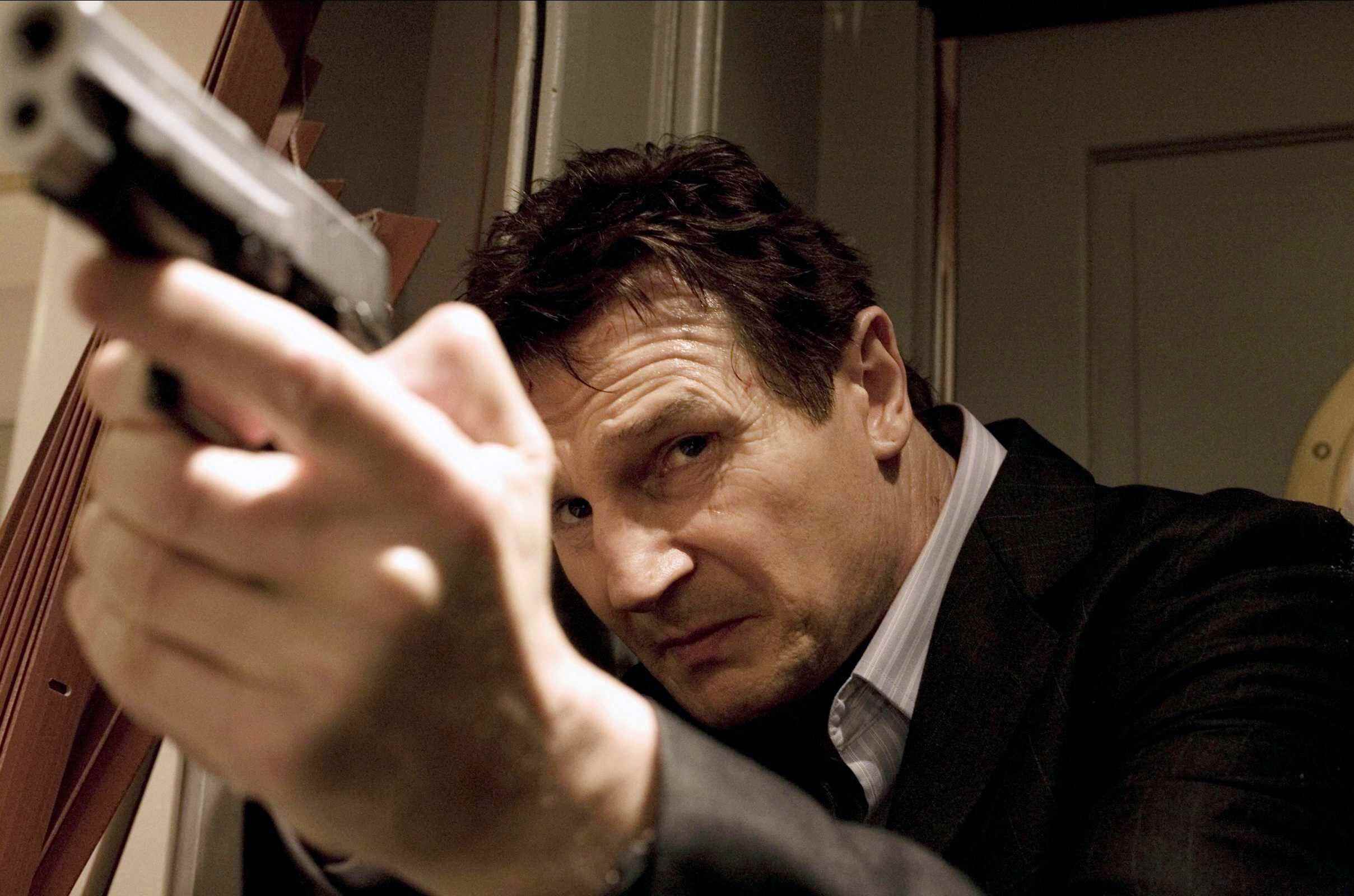 Liam Neeson Taken'da silahı yukarı doğrultuyor