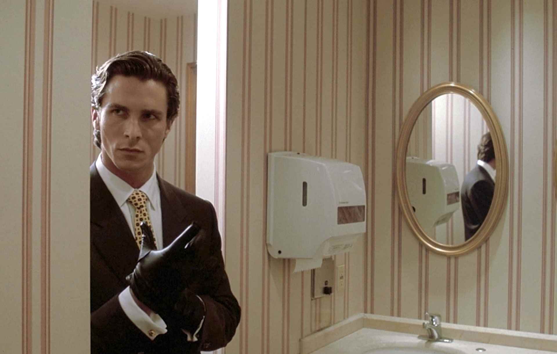Patrick Bateman (Christian Bale), American Psycho filminde siyah bir eldiven giyerken banyoya giriyor.