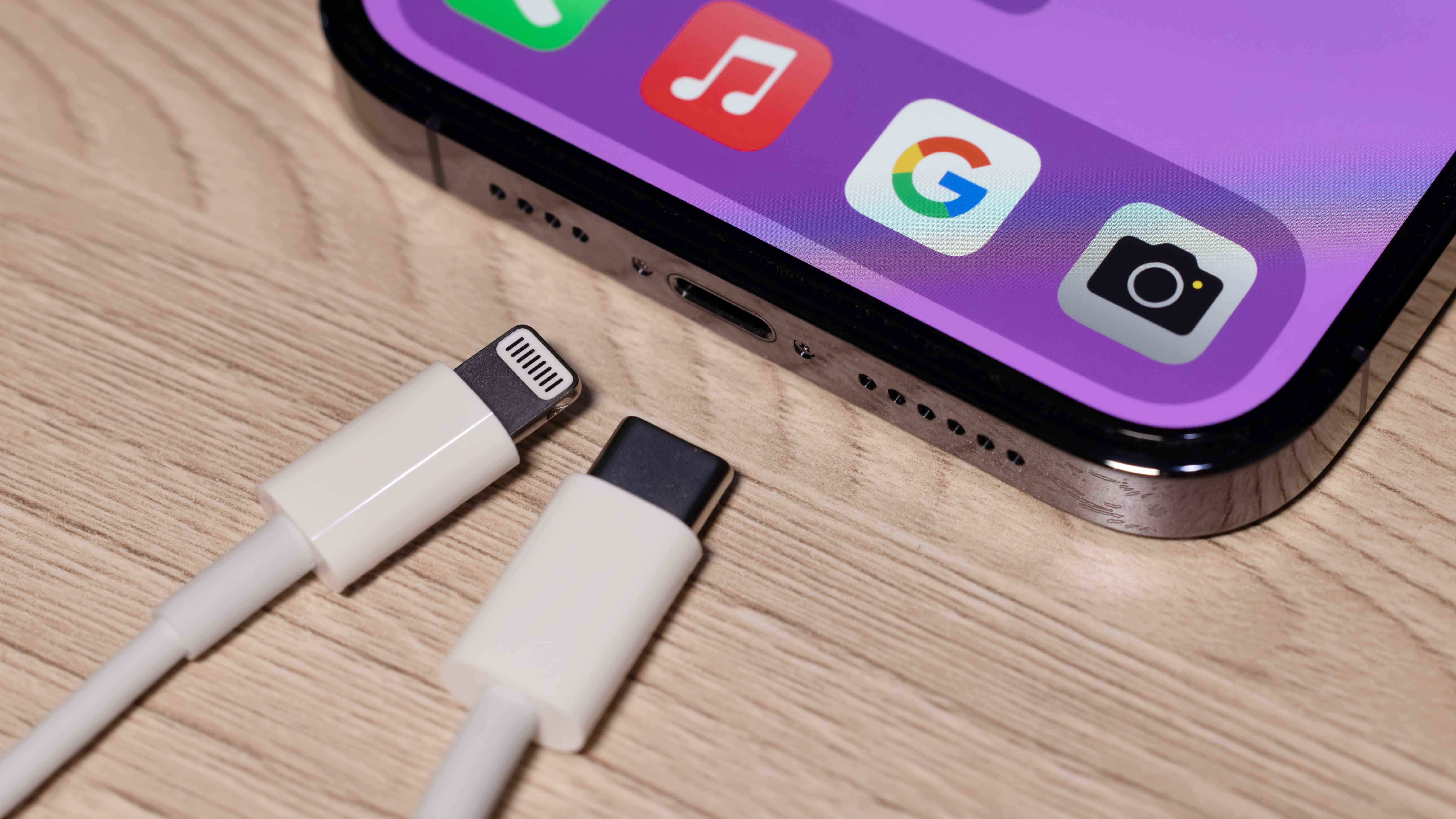 Bir iPhone 14'ün yanında Lightning şarj cihazı ve USB-C şarj cihazı