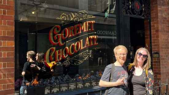 Diablo 4 çikolata dükkanı - PCGamesN personeli Ken ve Lauren, Lilith & Co mağazasının önünde duruyor.