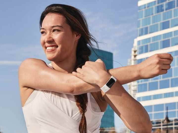 Antrenman sırasında omzunu esneten Fitbit Charge 5 giyen bir kadın.